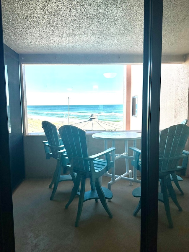 dining area featuring carpet, a textured ceiling, and a water view