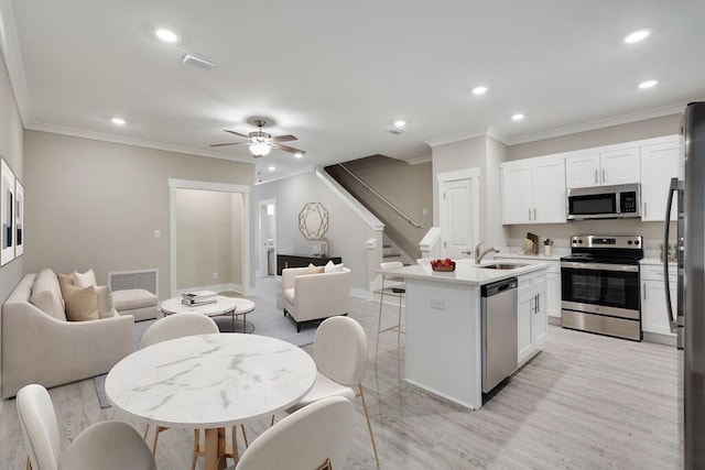 kitchen featuring ceiling fan, a kitchen island with sink, white cabinets, and appliances with stainless steel finishes