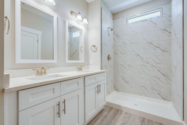 bathroom with vanity, a tile shower, and wood-type flooring