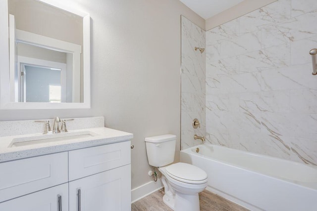 full bathroom with hardwood / wood-style floors, vanity, tiled shower / bath combo, and toilet