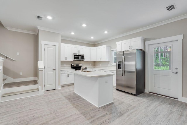 kitchen featuring white cabinets, appliances with stainless steel finishes, light wood-type flooring, and a kitchen island with sink