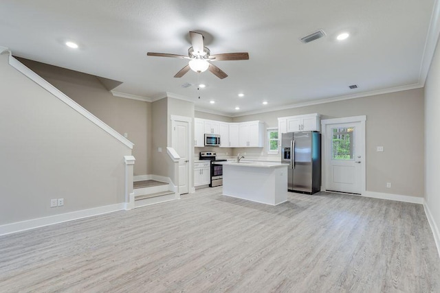 kitchen with a center island, light wood-type flooring, ornamental molding, appliances with stainless steel finishes, and white cabinetry