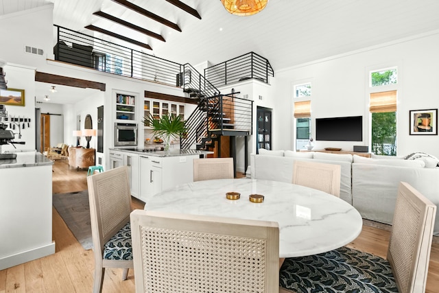 dining area featuring a towering ceiling, wood ceiling, and light hardwood / wood-style flooring