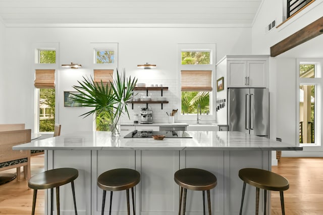 kitchen with a wealth of natural light, a breakfast bar area, and high quality fridge