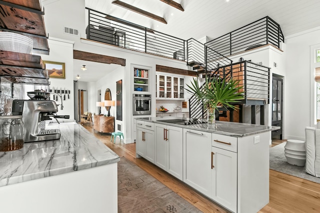 kitchen with light hardwood / wood-style floors, white cabinetry, a kitchen island, and stainless steel oven