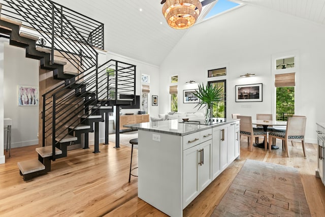 kitchen with a center island, high vaulted ceiling, light wood-type flooring, a wealth of natural light, and white cabinetry