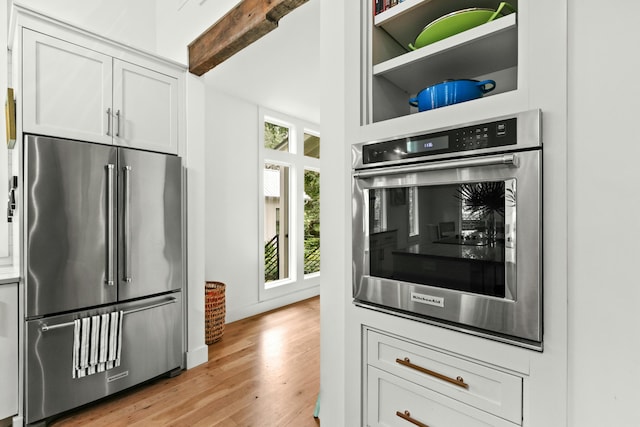 kitchen with appliances with stainless steel finishes, light hardwood / wood-style floors, and white cabinetry