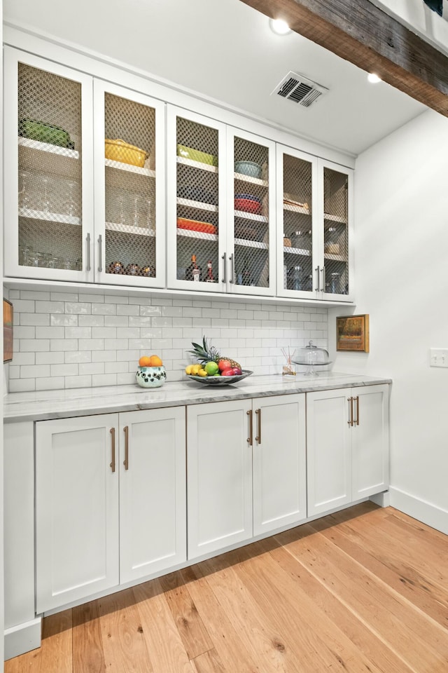 bar with white cabinets, beam ceiling, tasteful backsplash, and light hardwood / wood-style flooring