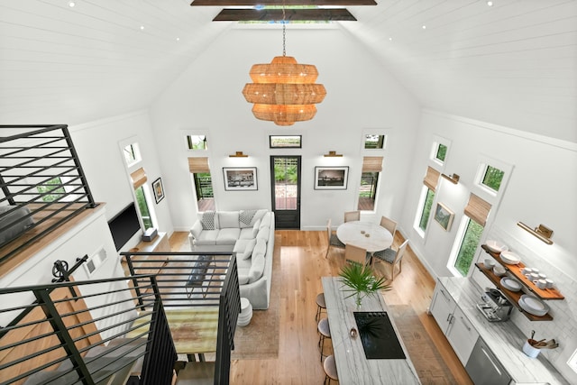 living room with an inviting chandelier, high vaulted ceiling, beamed ceiling, and light wood-type flooring