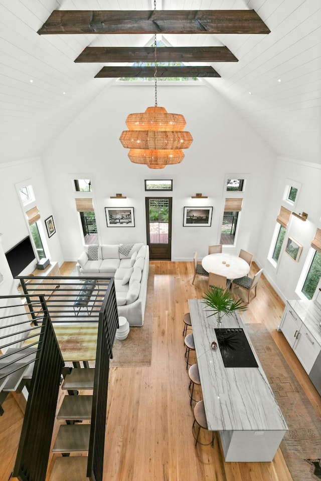 living room with a wealth of natural light, high vaulted ceiling, and light hardwood / wood-style flooring