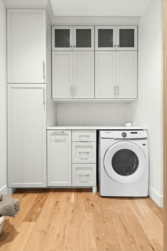 laundry area with cabinets, light wood-type flooring, and washer / clothes dryer