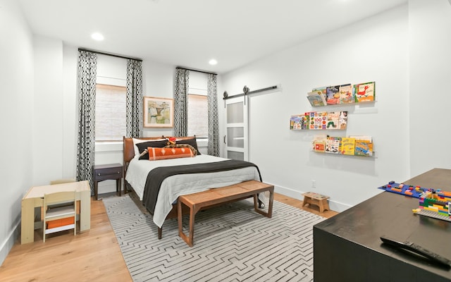 bedroom featuring a barn door and light hardwood / wood-style floors