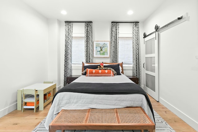 bedroom featuring a barn door and light wood-type flooring