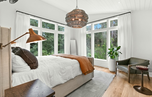 bedroom with an inviting chandelier, light hardwood / wood-style floors, wood ceiling, and vaulted ceiling