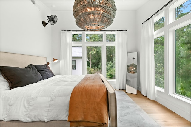 bedroom with light hardwood / wood-style flooring, multiple windows, and a notable chandelier