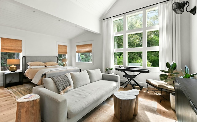 bedroom featuring vaulted ceiling with beams, light hardwood / wood-style floors, and multiple windows