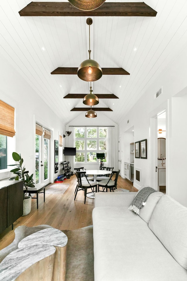 living room with hardwood / wood-style flooring, vaulted ceiling with beams, and a healthy amount of sunlight