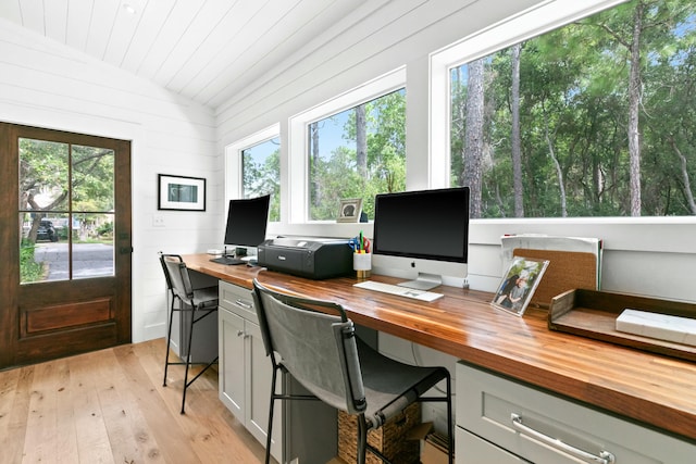 office area featuring plenty of natural light, wood walls, light wood-type flooring, and vaulted ceiling