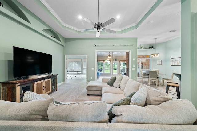 living room featuring light carpet, a tray ceiling, ceiling fan, and crown molding