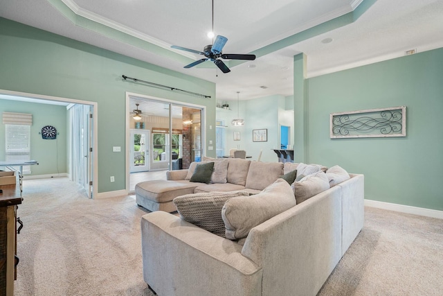 carpeted living room featuring plenty of natural light, ceiling fan, ornamental molding, and a tray ceiling