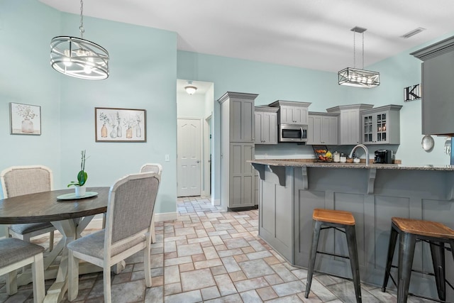 kitchen featuring pendant lighting, a kitchen breakfast bar, gray cabinetry, and kitchen peninsula