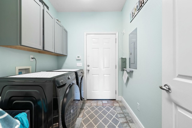 laundry room with washer and dryer, a barn door, cabinets, and electric panel