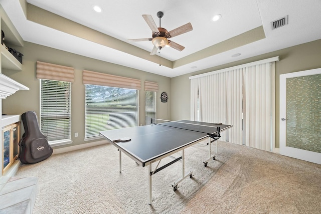 game room with carpet flooring, a tray ceiling, and ceiling fan