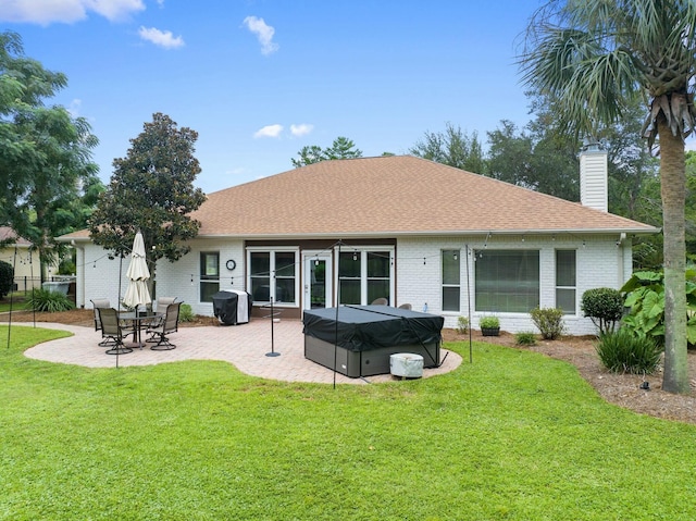 rear view of house with a yard, a patio, and a hot tub