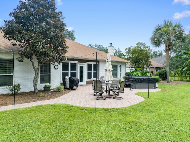 back of house featuring a yard, a patio, and a hot tub