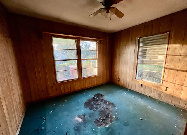 spare room featuring carpet, ceiling fan, and wooden walls