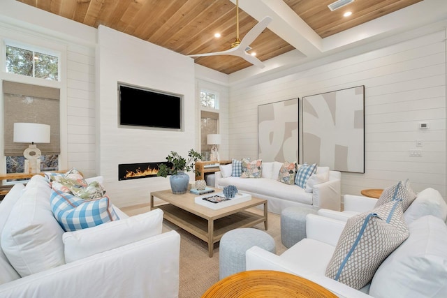 living room featuring a large fireplace, ceiling fan, beam ceiling, wooden ceiling, and wood walls