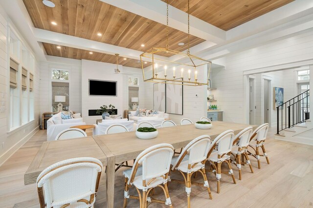 dining room featuring light hardwood / wood-style floors, wooden ceiling, beam ceiling, and a chandelier