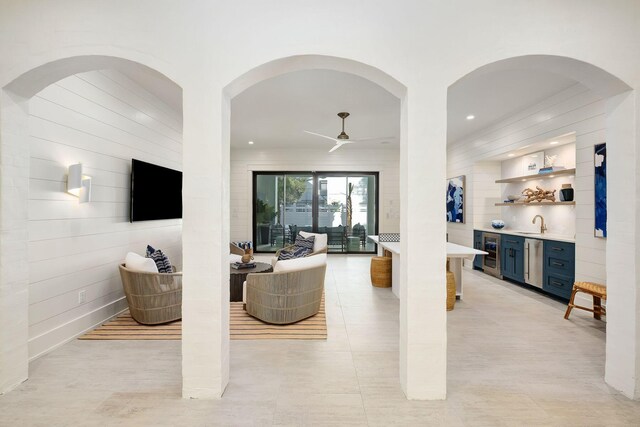 living room with wine cooler, ceiling fan, sink, and light tile patterned floors