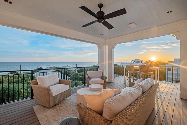 deck at dusk featuring an outdoor living space, a water view, and ceiling fan