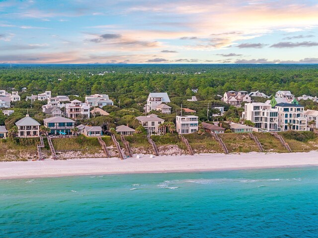 aerial view at dusk featuring a view of the beach and a water view