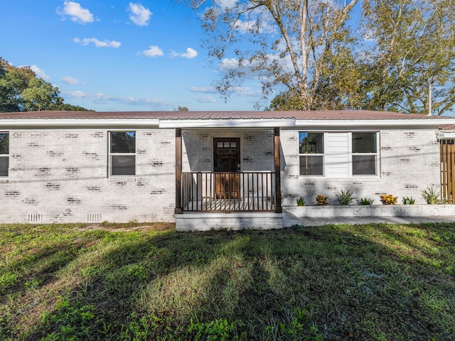 274 S 20th St, Defuniak Springs, FL 32435 - view of front facade with brick siding, a front lawn, crawl space, metal roof, and covered porch