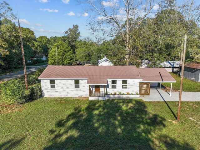 back of property with a carport and a yard