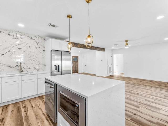 kitchen featuring sink, wine cooler, appliances with stainless steel finishes, decorative light fixtures, and white cabinetry