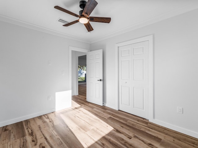 unfurnished bedroom with a closet, ceiling fan, crown molding, and light hardwood / wood-style floors