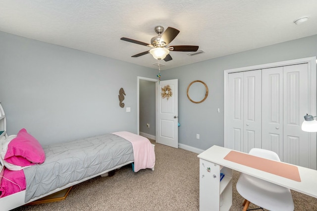 bedroom with a textured ceiling, a closet, ceiling fan, and light colored carpet