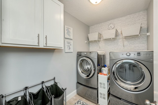 laundry room featuring cabinets, light tile patterned floors, washer and dryer, and a textured ceiling