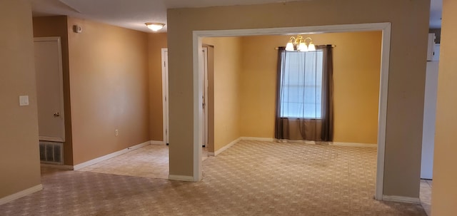 empty room with light carpet and an inviting chandelier