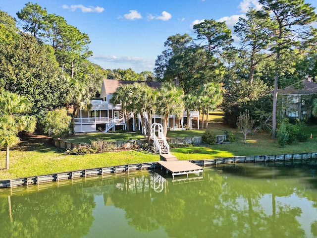 rear view of property with stairway, a lawn, and a water view