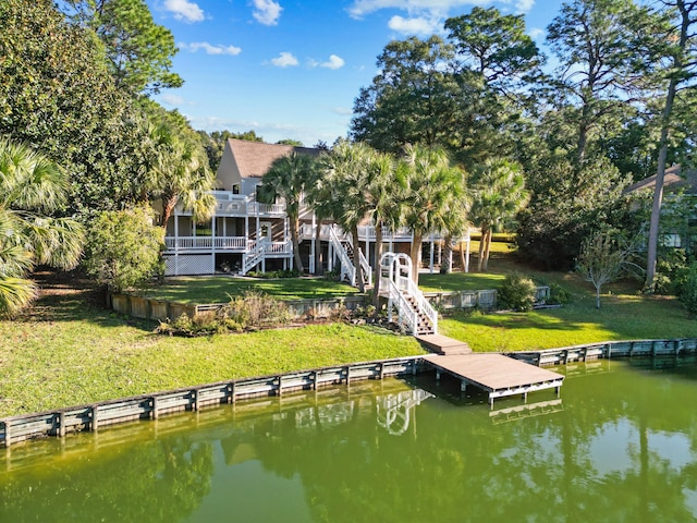 view of dock with a deck with water view and a lawn