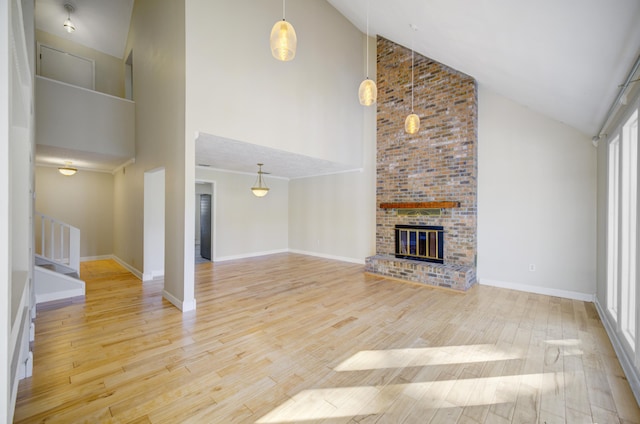 unfurnished living room featuring a fireplace, light hardwood / wood-style flooring, and high vaulted ceiling