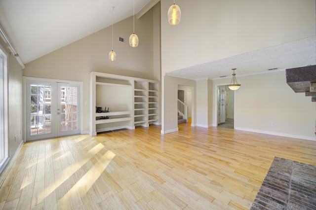 unfurnished living room featuring french doors, a textured ceiling, high vaulted ceiling, and hardwood / wood-style floors