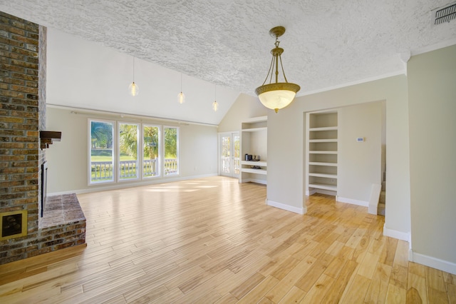 unfurnished living room featuring vaulted ceiling, light hardwood / wood-style flooring, built in shelves, a textured ceiling, and a fireplace