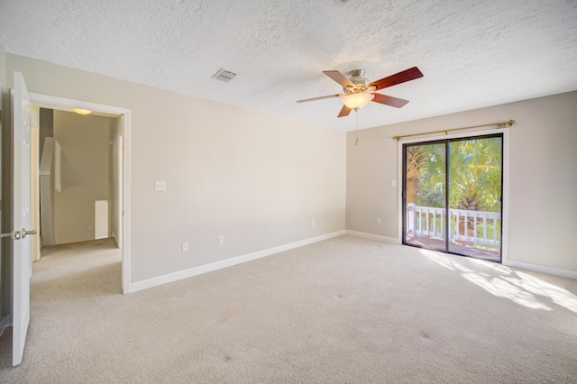 spare room with a textured ceiling, ceiling fan, and light carpet