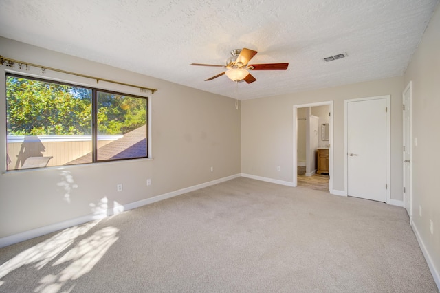 unfurnished room with ceiling fan, light colored carpet, and a textured ceiling