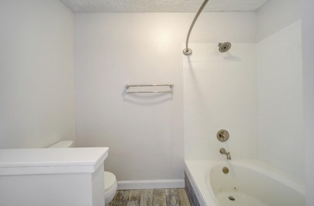 bathroom with toilet, wood-type flooring, a textured ceiling, and tiled shower / bath